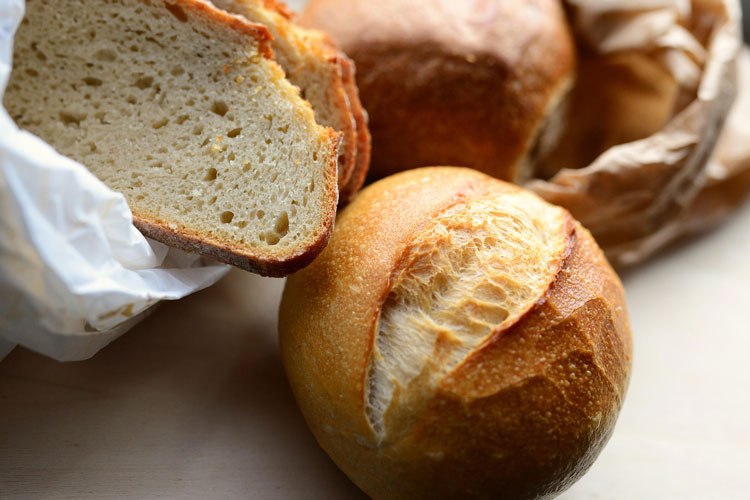 Frisches Brot und Br&ouml;tchen auf Papier, Nahaufnahme mit knuspriger Kruste und weicher Krume