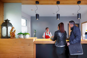 Hotelrezeption mit Holztheke, Dekoration und zwei Gästen beim Check-in