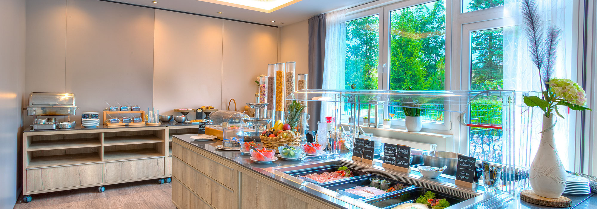 Helles Frühstücksbuffet mit frischem Obst, Müsli, Brot und Aufschnitt in modernem Raum