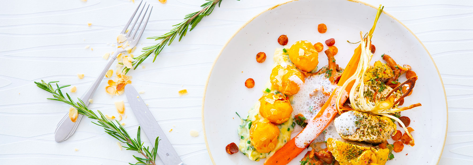 Fein angerichtetes Gourmetgericht mit Gemüse, Kräutern, Sauce und Schaum auf weißem Teller, dekorativ serviert